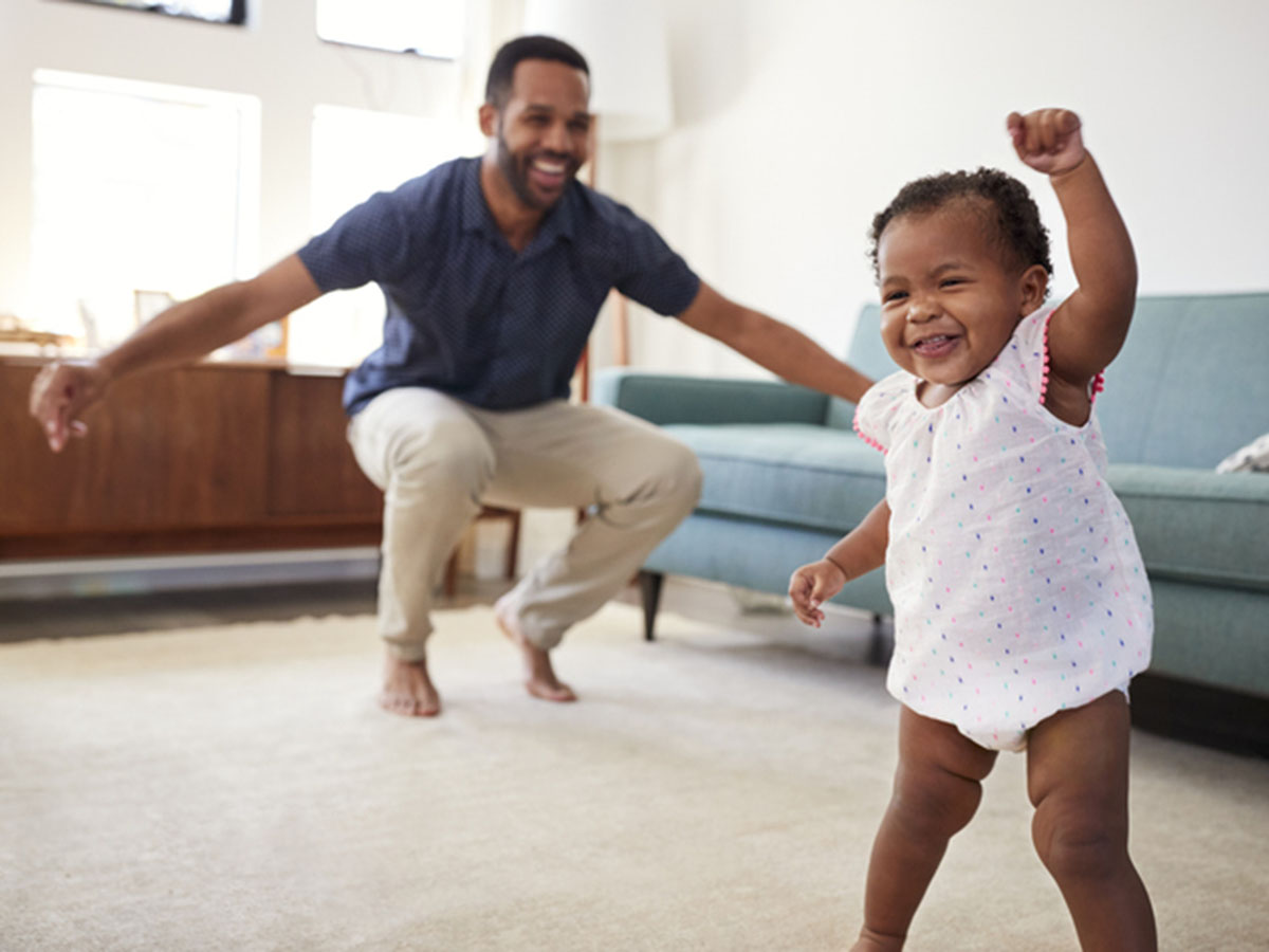 Baby Daughter Dancing With Father In Lounge At Home